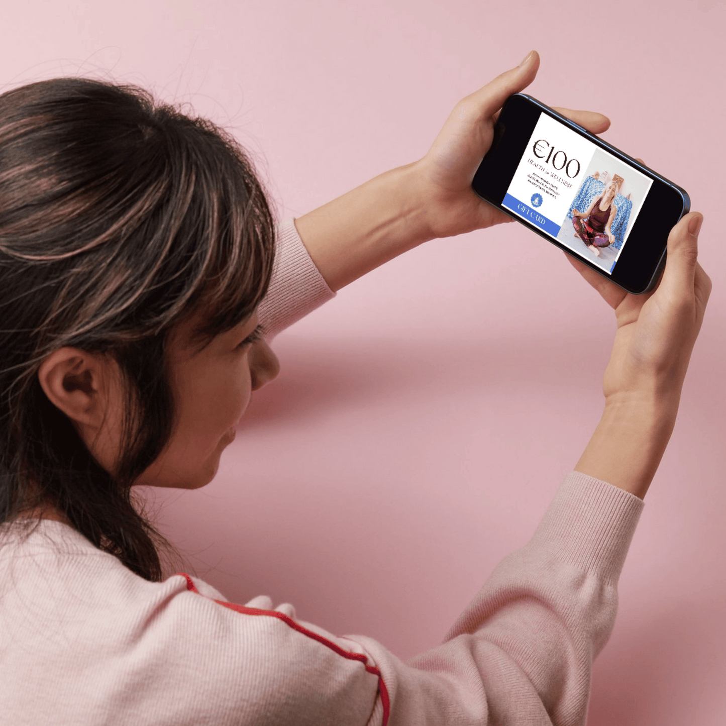 Person holding a phone displaying the Wellness with Cecelia digital gift card, ready to redeem for yoga, breathwork, and holistic wellness experiences.